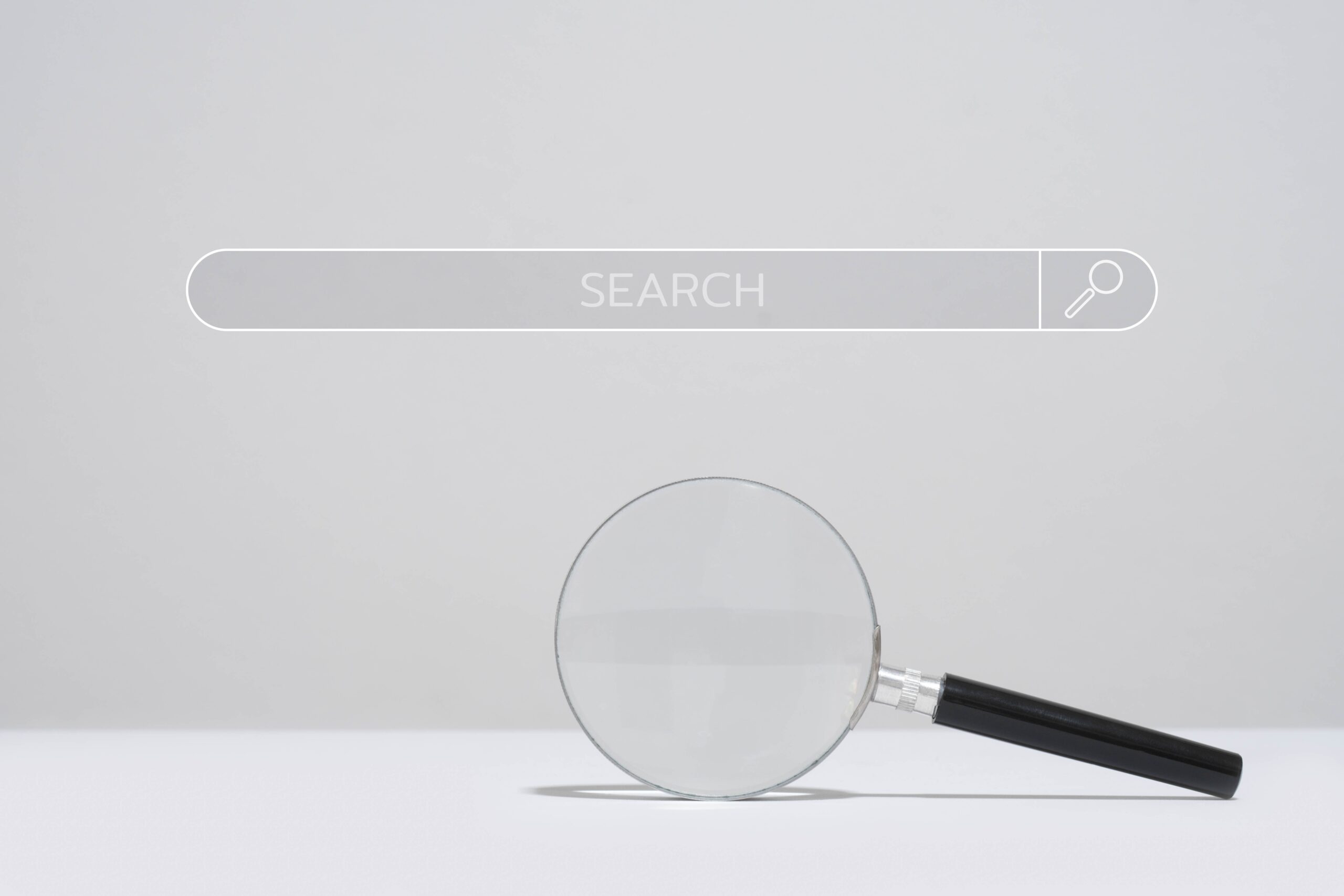 Magnifying,glass,below,a,search,bar,on,a,plain,background,